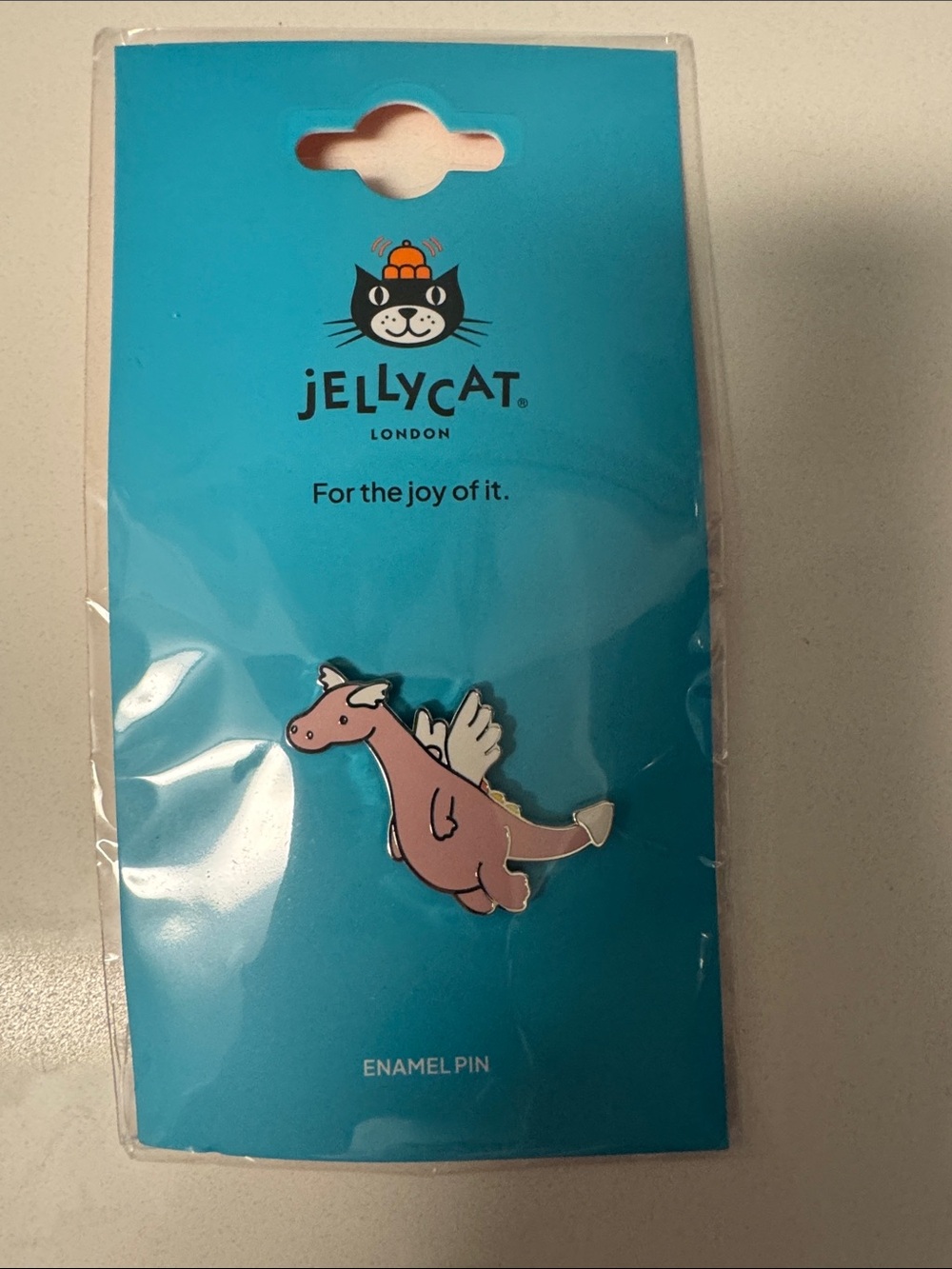 This is an official Jellycat Duskrise Dragon enamel pin badge featuring the pink